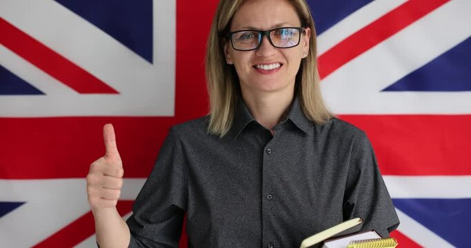 Blonde woman promoting language learning. Cheerful English lecturer standing in front of British flag and encouraging students to study slow motion
