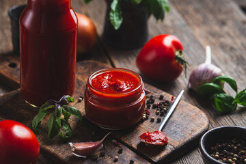 Ketchup in a jar. Tomato sauce on a dark background