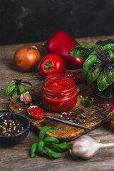 Ketchup in a jar. Tomato sauce on a dark background