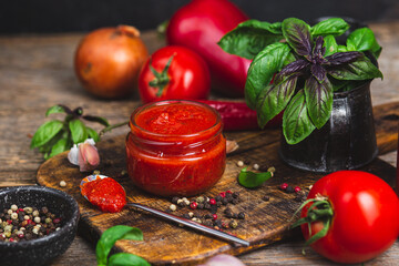 Ketchup in a jar. Tomato sauce on a dark background