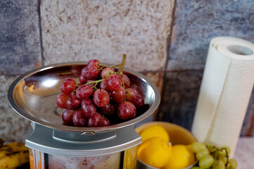 Various fruits on a kitchen countertop and on a kitchen scale.
