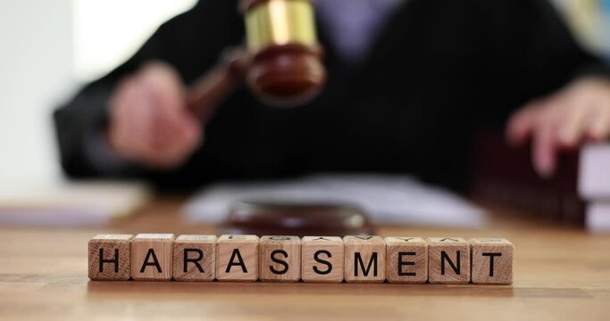 Word Harassment consisting of wooden cubes against lawyer banging gavel in court. Conceptual of aggressive physical and verbal actions towards victim