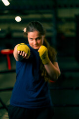 portrait focused Boxer girl in yellow boxing bandages standing in a boxing stance on a dark...