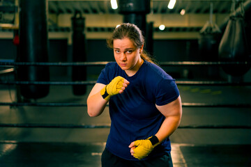portrait focused Boxer girl in yellow boxing bandages standing in a boxing stance on a dark...