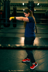 portrait focused Boxer girl in yellow boxing bandages standing in a boxing stance on a dark...