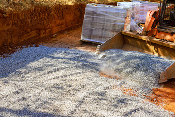 By using tractor, prepare basis of new road by laying crushed stone gravel filled with crushed stone