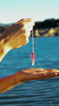 Women's hands holding a pendulum in nature
