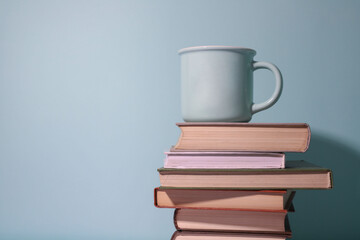 There is a stack of books on a blue background, with a blue cup on top