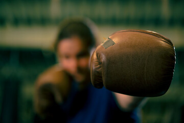 woman in boxing gloves posing in a sassy and competitive fight in a boxing ring before a fight with...