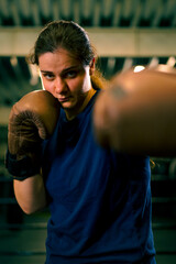 portrait of a woman in boxing gloves posing in a cheeky and competitive fight in a boxing ring...