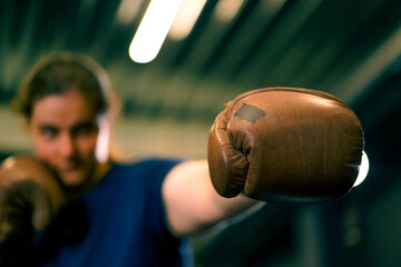 woman in boxing gloves posing in a sassy and competitive fight in a boxing ring before a fight with...