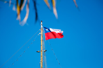 Red, blue, and white Chilean flag waving with blue sky and as background	