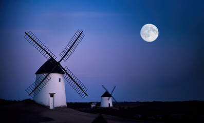 ancien moulin à vent blanc à la chaux avec toiture noire la nuit avec la pleine lune dans le ciel