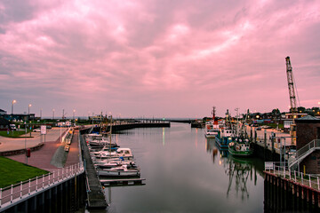 Der kleine Hafen, mit Hafen ein und Ausfahrt im frühen Morgen rot. Noch erleuchten Laternen die...