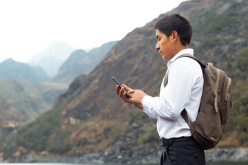 Alumno joven campesino en un lago mientras usa un teléfono inteligente mirada a un espacio publicidad y aislada en un fondo naturaleza, contactar, celular,comunicación,estilo de vida