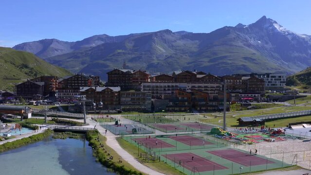 Drone view of people playing tennis in the ski station of Tignes with the Lavachet district and mountains in bakcground