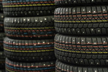 Sale of car tires for sale in the store. Many new winter tires lie horizontally. There is space for...