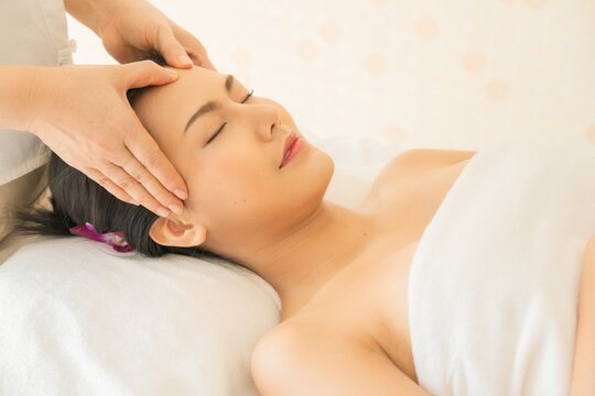 Close-up facial massage. Spa skin and body care. Beautiful young Asian woman getting spa massage treatment at beauty spa salon. Facial beauty treatment. Beauty photo concept, skin care, facial massage