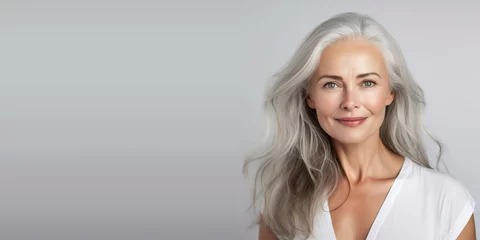 Poster Beautiful woman with smooth healthy face skin. Gorgeous aging mature woman with long gray hair and happy smiling. Beauty and cosmetics skincare advertising concept. With copy space. © Fotos97