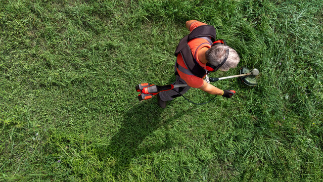 High angle view of modern gardener mows the grass with lawn mower.