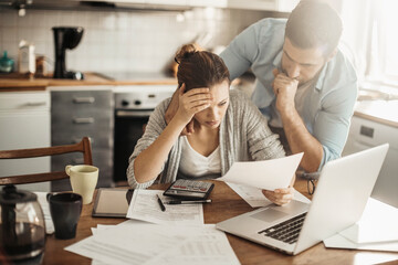 Stressed young couple doing financials in the kitchen - obrazy, fototapety, plakaty