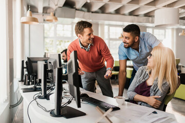 Diverse group of young colleagues working on the computer together in the office