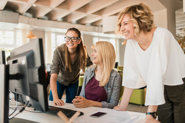 Diverse group of young colleagues working on the computer together in the office