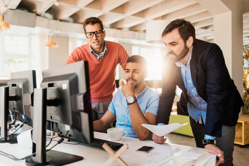 Diverse group of young colleagues working on the computer together in the office