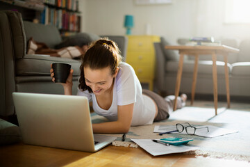 Young woman using the laptop on the floor of her living room at home