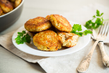 Cooked fried fish cutlets in a plate with herbs. - obrazy, fototapety, plakaty