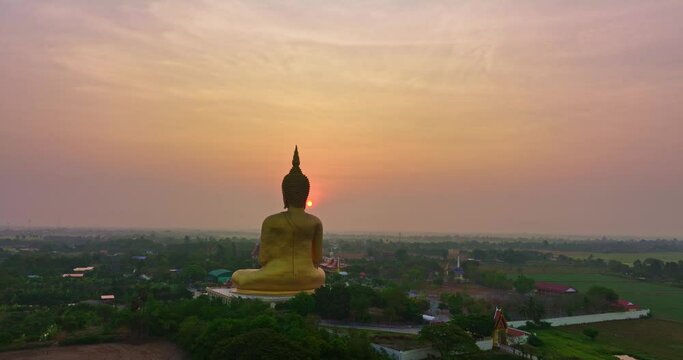 ..aerial view colorful sky in sunrise the yellow sun at golden big buddha a popular landmark in Thailand..video 4K Nature video High quality footage for worship and travel concept..green rice field.