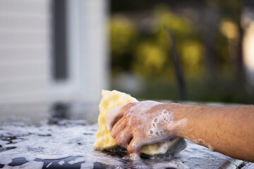 hand with a washcloth and soap suds on a black surface. Hand with a yellow-green washcloth....