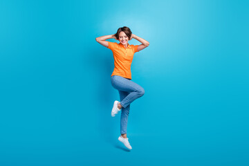 Fototapeta na wymiar Full size photo of gorgeous girl dressed stylish polo denim trousers flying hold arms behind head isolated on blue color background