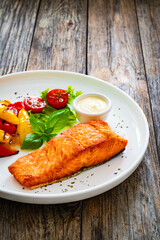 Seared salmon steak with grilled bell pepper and mayonnaise on wooden table
