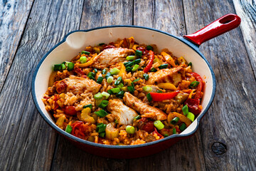 Jambalaya one pot dish - fried chicken breasts with white rice, tomatoes, bell pepper and celery on wooden table
