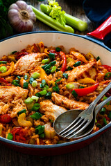Jambalaya one pot dish - fried chicken breasts with white rice, tomatoes, bell pepper and celery on wooden table
