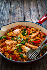 Jambalaya one pot dish - fried chicken breasts with white rice, tomatoes, bell pepper and celery on wooden table

