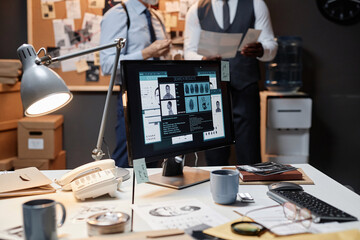 Close up of cluttered desk in detectives office with personal profile on computer screen, copy space