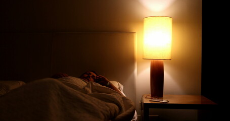 Person turns night stand light ON and gets out of bed - obrazy, fototapety, plakaty