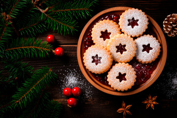 Obraz na płótnie Canvas Linzer cookies with sweet jam and fir tree branches on wooden table. Top view