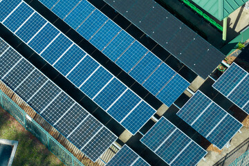 Aerial view of blue solar photovoltaic panels mounted on fenced backyard for producing clean...