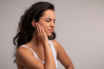 Woman having ear pain, touching her painful cheek - obrazy, fototapety, plakaty