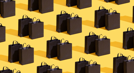 Pattern made from black paper shopping bags on yellow background. Black friday sale, shopping...
