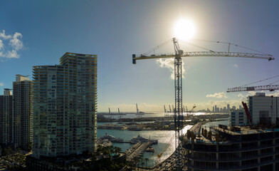 New construction site of developing residense in american urban area. Industrial tower lifting cranes in Miami, Florida. Concept of housing growth in the USA