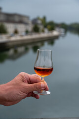 Tasting of Cognac strong alcohol drink in Cognac region, Charente with view on ols houses and streets of Cognac town on background, France