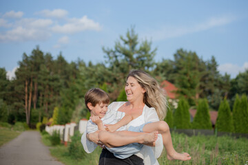 Fototapeta premium Single parents. Mom and son have fun and indulge during walk on warm summer day on rural road .