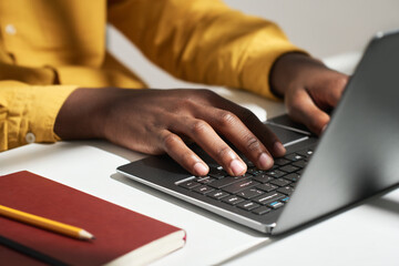 Hands of young male solopreneur pressing buttons of laptop keyboard while sitting by workplace in...