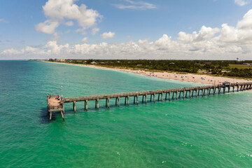 Venice fishing pier in Florida on sunny summer day. Bright seascape with surf waves crashing on sandy beach