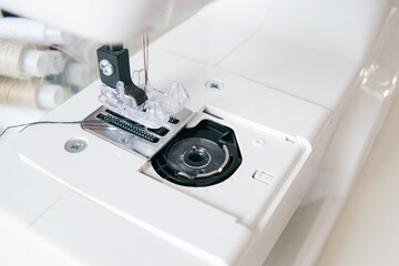 working part of an antique sewing machine. Selective focus on plastic shuttle and sewing needle. Close-up