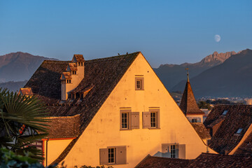 Beautiful waning moon over the old city of Rapperswil, Canton St. Gallen, Switzerland. - obrazy, fototapety, plakaty
